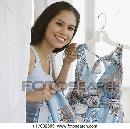 Woman holding dress in fitting room View Large Photo Image Stock Photo - Woman holding dress in fitting room. Fotosearch