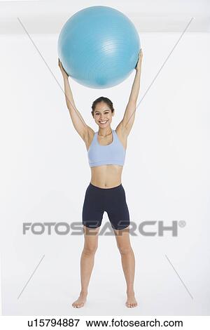 Woman holding exercise ball over head View Large Photo Image Stock Photo - Woman holding exercise ball over head. Fotosearch