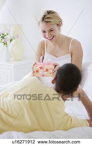 Stock Image - Woman holding gift from husband. Fotosearch