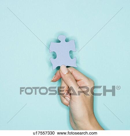 Stock Image - Woman holding jigsaw puzzle piece. Fotosearch