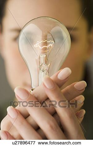 Stock Photo - Woman holding light bulb in front of face. Fotosearch