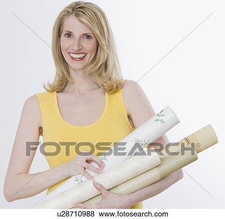 Stock Photo - Woman holding rolls of wallpaper. Fotosearch
