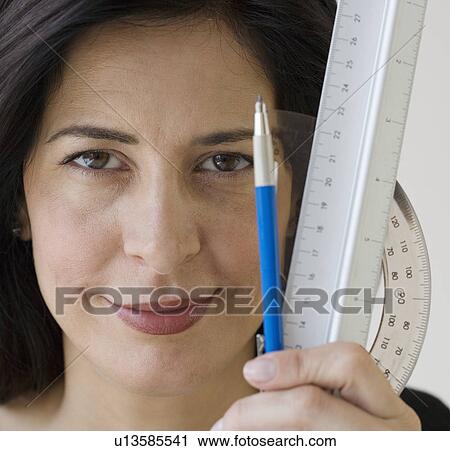 Stock Image - Woman holding ruler, protractor and pencil. Fotosearch