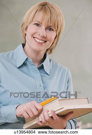 Picture - Woman holding school books and pencils. Fotosearch