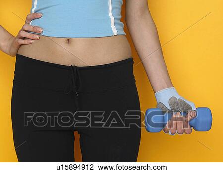 Woman in athletic gear holding dumbbell View Large Photo Image Stock Image - Woman in athletic gear holding dumbbell. Fotosearch