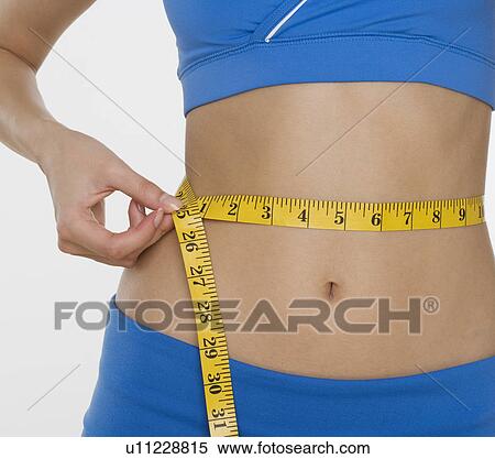 Woman in athletic gear measuring waist View Large Photo Image Stock Photography - Woman in athletic gear measuring waist. Fotosearch