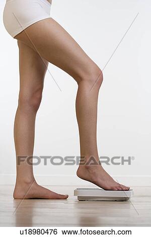 Woman in underwear stepping on scale View Large Photo Image Stock Photograph - Woman in underwear stepping on scale. Fotosearch