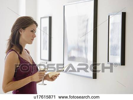 Stock Image - Woman looking at artwork in gallery. Fotosearch