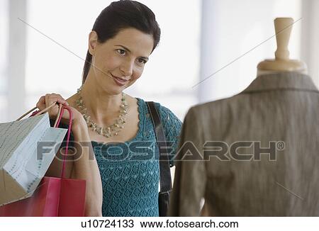 Stock Image - Woman looking at clothing in store. Fotosearch