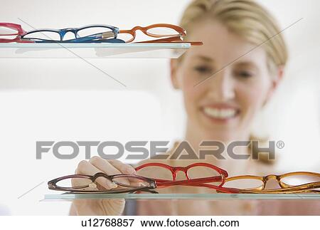 Woman looking at eyeglasses in store View Large Photo Image Stock Photo - Woman looking at eyeglasses in store. Fotosearch