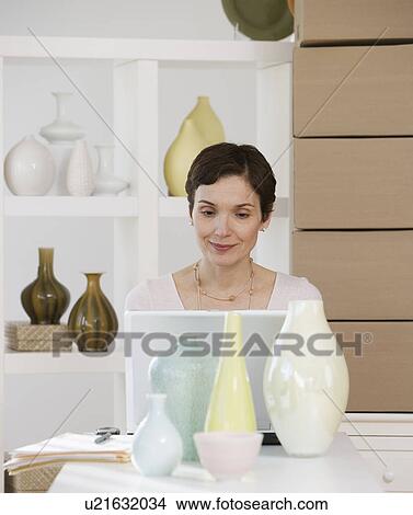 Woman looking at laptop in pottery store View Large Photo Image Picture - Woman looking at laptop in pottery store. Fotosearch