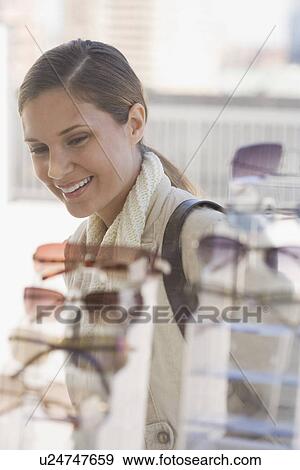 Stock Photo - Woman looking at sunglasses in shop window. Fotosearch