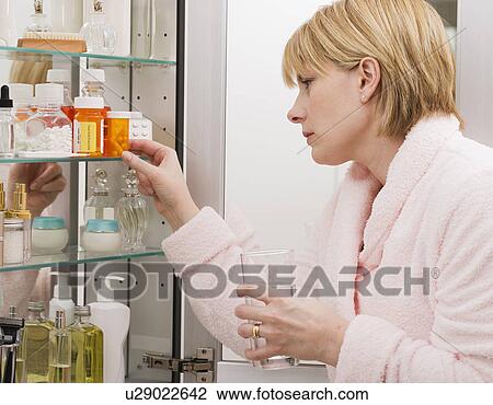 Woman looking in medicine cabinet View Large Photo Image Stock Image - Woman looking in medicine cabinet. Fotosearch
