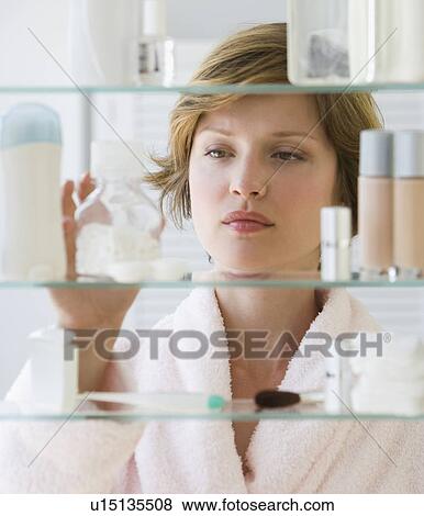 Stock Photo - Woman looking in medicine cabinet. Fotosearch