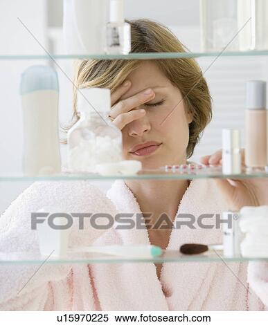 Stock Photography - Woman looking in medicine cabinet. Fotosearch