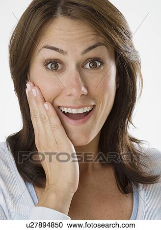 Stock Image - Woman looking surprised with hand on cheek. Fotosearch
