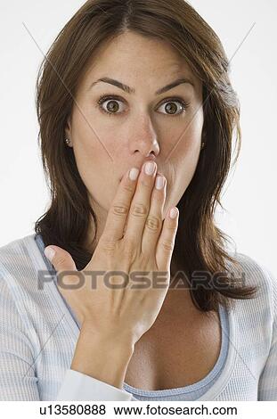 Stock Photo - Woman looking surprised with hand over mouth. Fotosearch