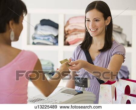 Stock Photo - Woman paying at clothing store. Fotosearch
