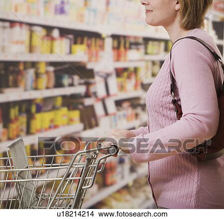 Picture - Woman pushing shopping cart in grocery store. Fotosearch