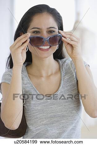 Stock Photo - Woman putting on sunglasses. Fotosearch