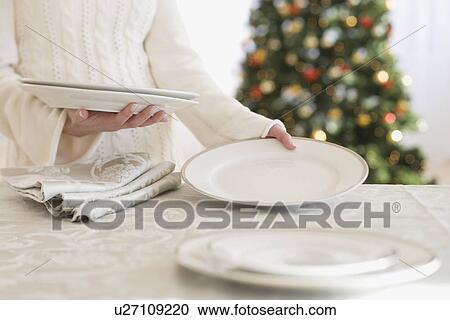Stock Image - Woman setting table at Christmas. Fotosearch