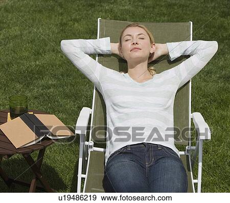 Stock Photo - Woman sitting in lounge chair. Fotosearch