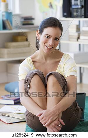 Stock Photo - Woman sitting on floor hugging knees. Fotosearch