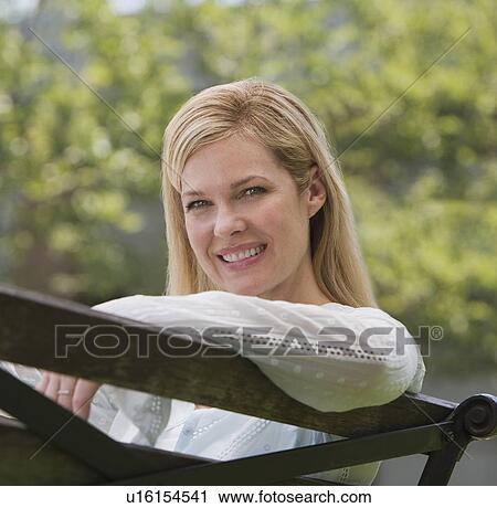 Woman sitting on park bench View Large Photo Image Stock Image - Woman sitting on park bench. Fotosearch