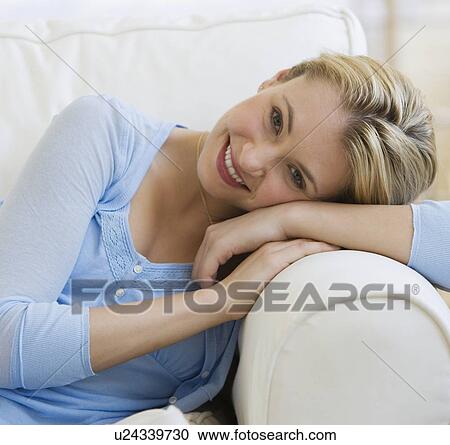 Stock Image - Woman sitting on sofa. Fotosearch