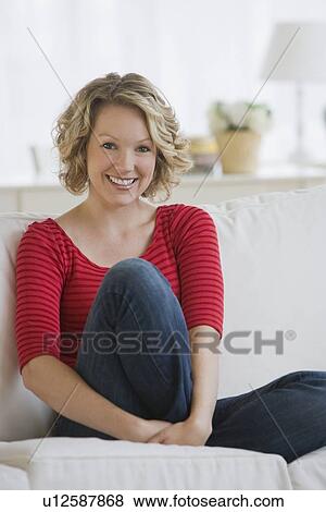 Stock Photo - Woman sitting on sofa. Fotosearch