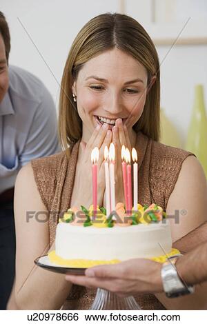 Stock Photograph - Woman smiling at birthday cake. Fotosearch