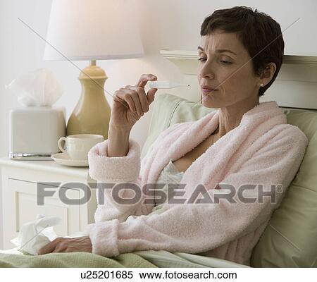 Woman taking own temperature in bed View Large Photo Image Stock Photography - Woman taking own temperature in bed. Fotosearch