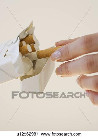 Stock Photo - Woman talking cigarette out of pack. Fotosearch
