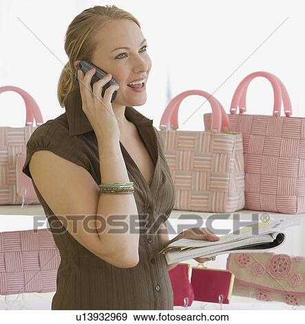 Stock Photo - Woman talking on cell phone in boutique. Fotosearch