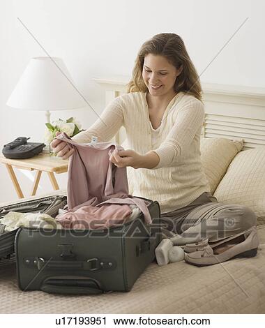Stock Image - Woman unpacking in hotel room. Fotosearch