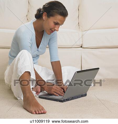 Stock Photo - Woman using laptop on floor. Fotosearch