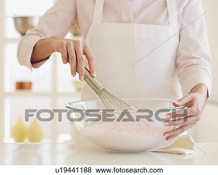Stock Photo - Woman wearing apron and mixing batter . Fotosearch