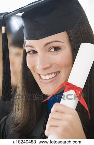 Stock Image - Woman wearing graduation cap and gown with diploma. Fotosearch