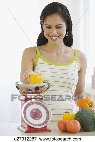 Woman weighing vegetables in kitchen View Large Photo Image Stock Photo - Woman weighing vegetables in kitchen. Fotosearch