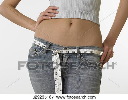 Stock Photo - Woman with bare midriff using tape measure as belt. Fotosearch
