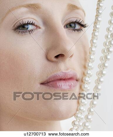 Stock Image - Woman with pearl necklace against face. Fotosearch