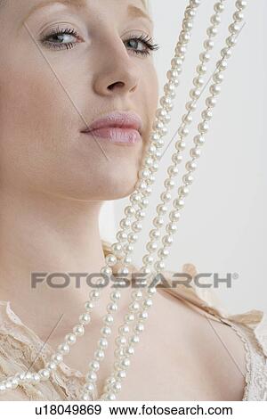 Stock Photo - Woman with pearl necklace against face. Fotosearch