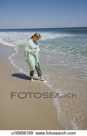Stock Photo - Woman wrapped in blanket at beach. Fotosearch