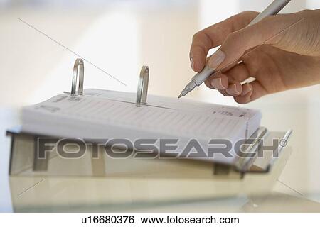 Stock Photograph - Woman writing on desk calendar. Fotosearch