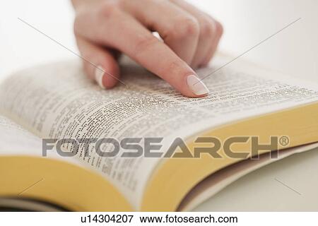 Stock Photo - Woman's finger on page in Bible. Fotosearch