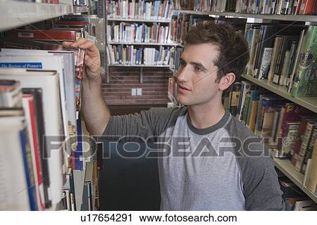 Stock Image - Young man in library. Fotosearch