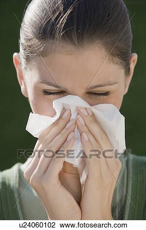 Stock Image - Young woman blowing nose. Fotosearch
