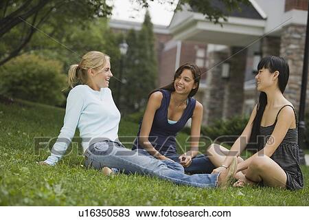 Young women talking in grass View Large Photo Image Stock Image - Young women talking in grass. Fotosearch