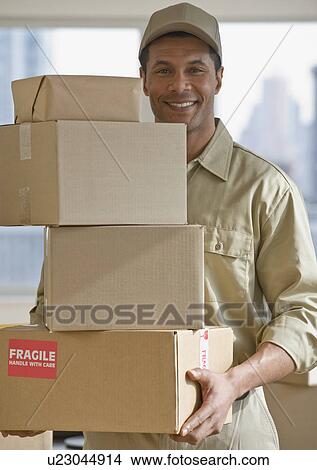 African delivery man carrying stack of packages View Large Photo Image Picture - African delivery man carrying stack of packages. Fotosearch