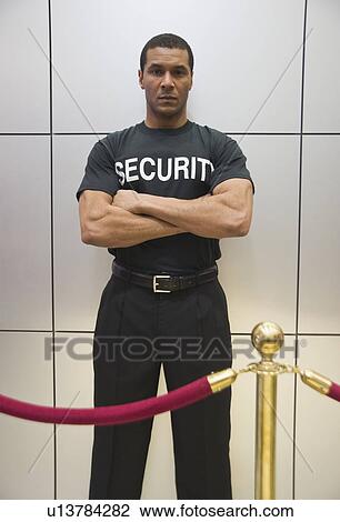Stock Image - African male bouncer behind velvet rope. Fotosearch